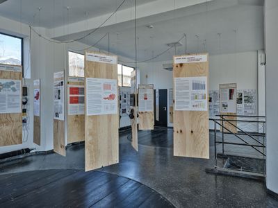 Blick in die Ausstellung im aut mit Schilderwald "geld macht raum" (im Raum) und Zeitstrahl "50 Jahre DOWAS" (an Wänden)